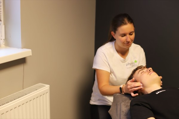 Physiotherapeutin im Gespräch mit einem Patienten während der Befundung