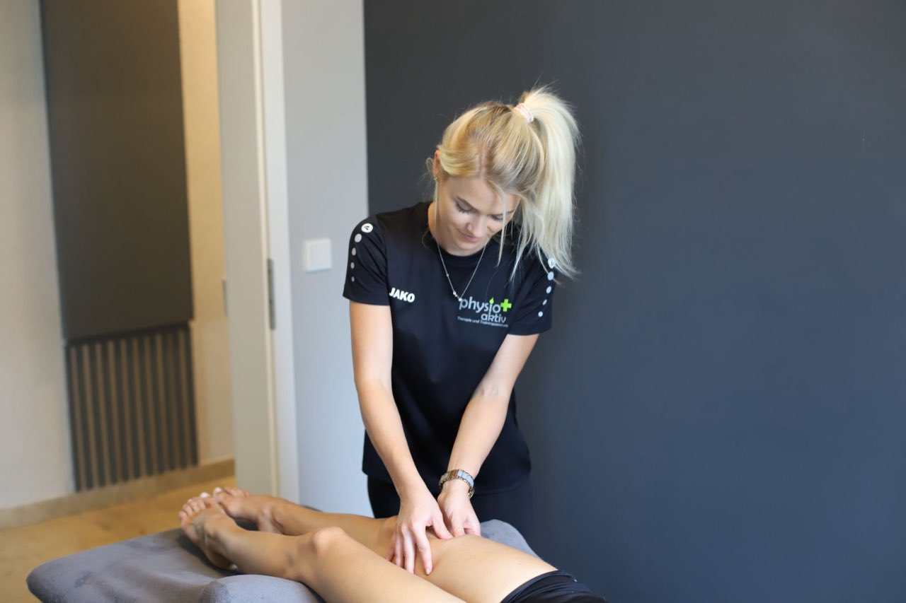 Physiotherapeutin massiert die Beinmuskulatur einer Patientin