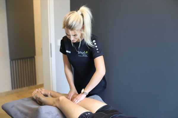 Physiotherapeutin behandelt die Beinmuskulatur einer Patientin
